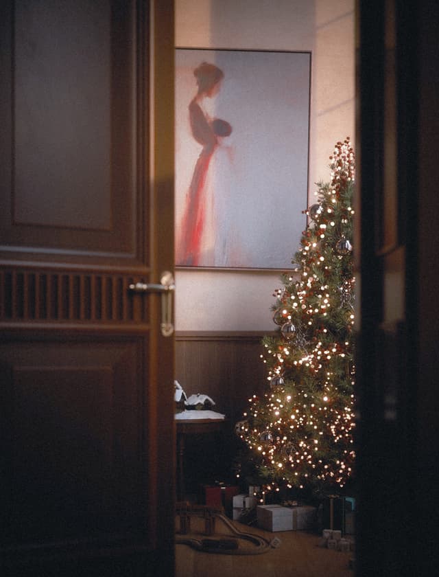Christmas card featuring a cozy living room with a decorated tree, gifts, and vintage toy train