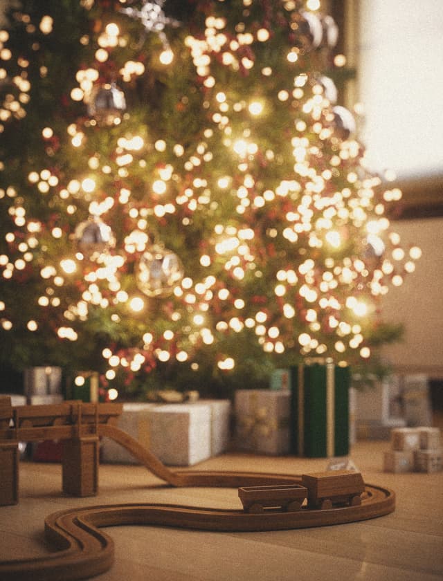 Christmas card featuring a cozy living room with a decorated tree, gifts, and vintage toy train