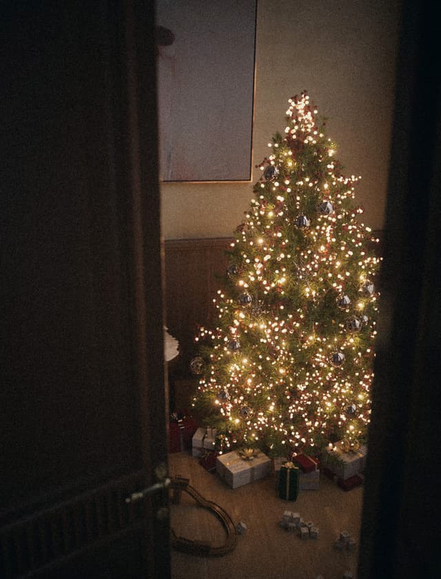 Christmas card featuring a cozy living room with a decorated tree, gifts, and vintage toy train